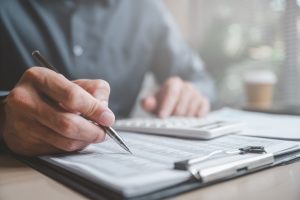 請求書の立替払いを利用する際の手数料や資金繰りを電卓と書類を使って計算している手元