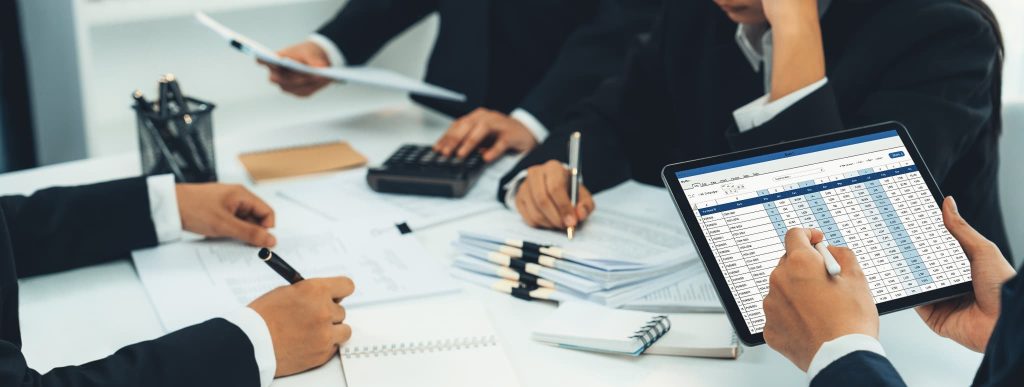 タブレット端末に表示された表計算データを見ながら議論する人々。キャッシュフロー計算書を用いて資金繰りや今後の財務戦略について話し合っている会議の様子