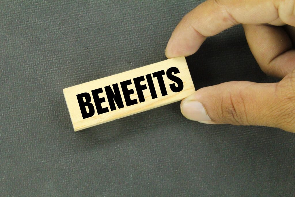 指で摘まみ上げられた「BENEFITS」と書かれた木製ブロック。当座貸越とは都度の審査なしで借り入れができるなどのメリットがあることを示す