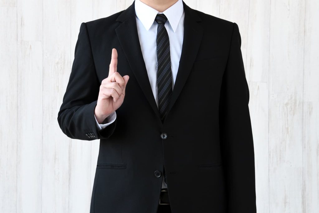 スーツを着た男性が人差し指を立ててポイントを解説しているポーズ。ノンバンクを利用する際の注意点やメリット、重要なポイントを説明している様子