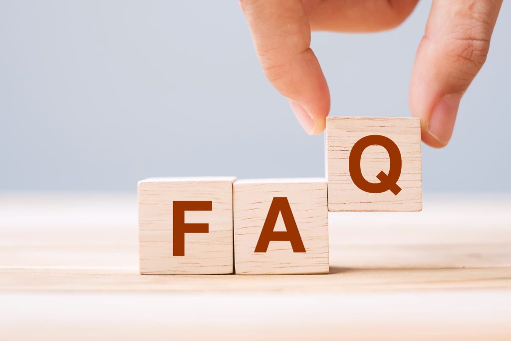手が木製ブロックを置いてFAQの文字を完成させている様子で開業資金に関するよくある質問を表している