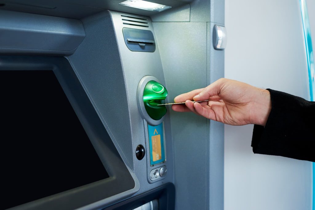 ATMにカードを挿入している手元。ビジネスローンは急な資金需要に対応できるメリットがある一方で、利用のしやすさには計画性が求められる
