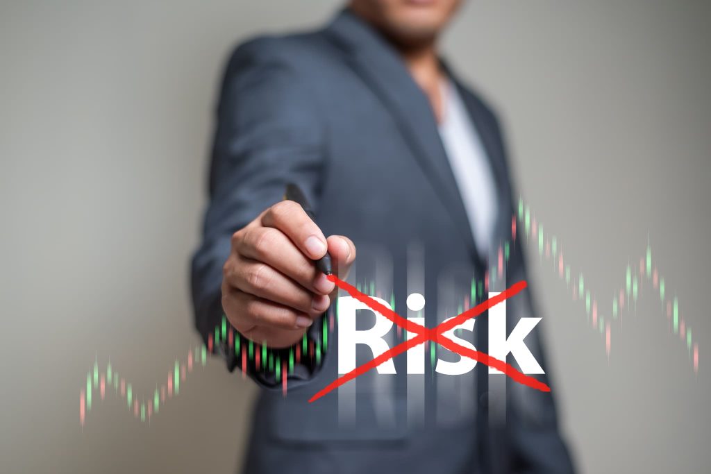 「Risk」の文字の上に赤いバツ印を描いている男性。債務超過とは倒産リスクが高い状態であり、早急な解消によってリスクを取り除く必要があることを示す