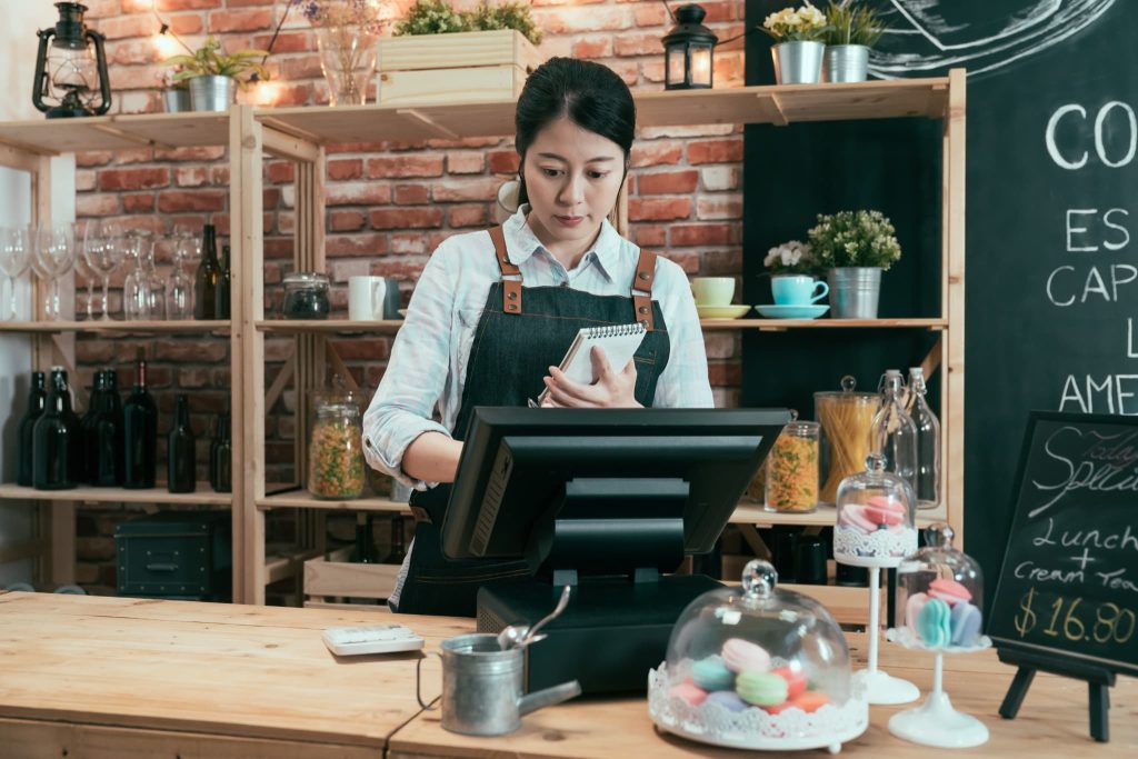 本業による現金の出入りである営業キャッシュフローを管理するため、レジの前で売上や帳簿を確認するカフェの店員