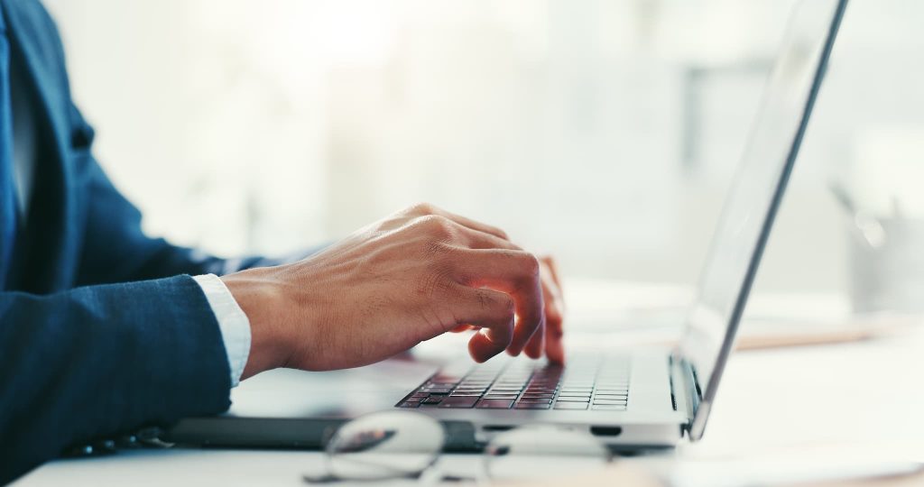 ノートパソコンのキーボードをタイピングするビジネスパーソンの手元。ローン審査なしの条件で借入が可能な金融機関をネット検索している様子