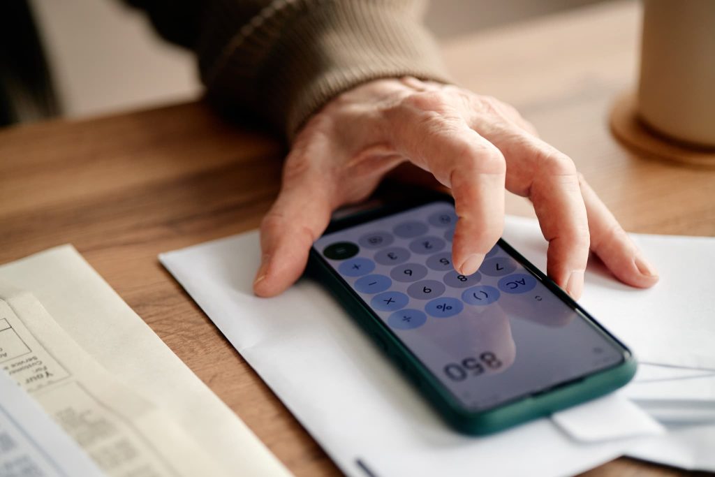 スマートフォンの計算機アプリを使って数字を計算する手元。月々の返済額や金利、必要となる運転資金の融資額を算出しているイメージ