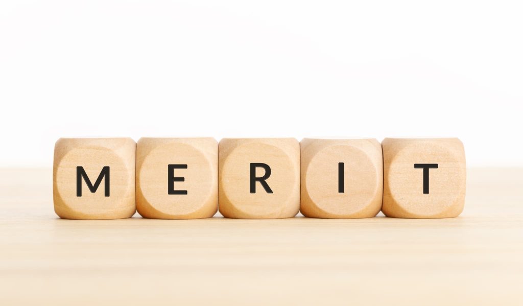 「MERIT」という文字が印字された5つの木製ダイス。法人向けビジネスローンを利用することで得られるメリットや利点を象徴するイメージ