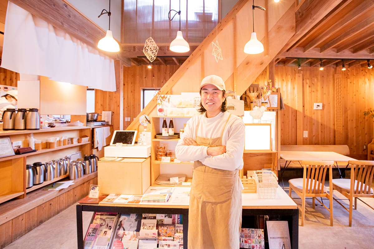 写真：店内で正面を向いて笑顔で立っているお店の人