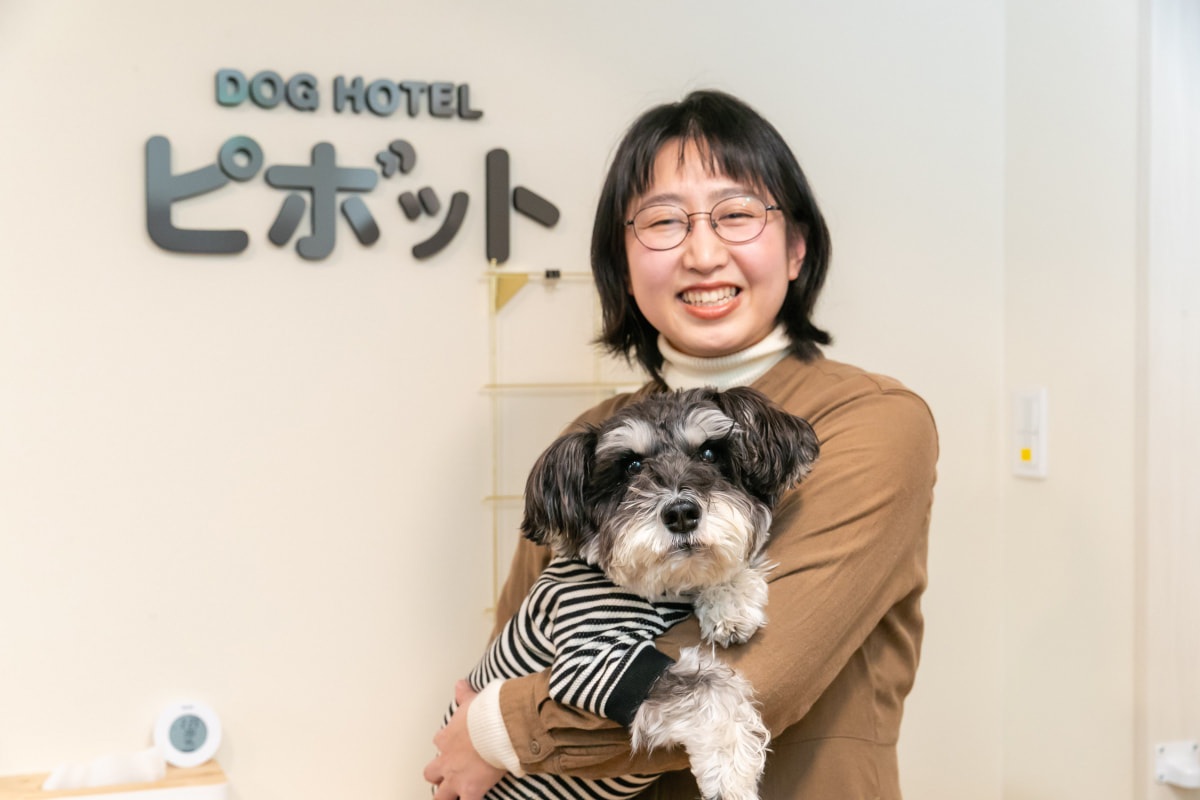 写真：正面を向いて笑顔で犬を抱いているお店の人