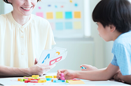 教室で先生が子供に教えている様子の写真