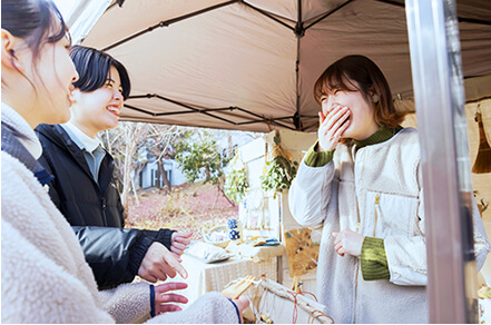 屋外の店舗で店員とお客さんが話す様子の写真