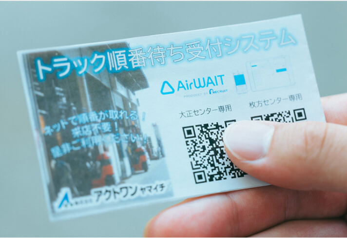写真:「トラック順番待ち受付システム」と書かれた名刺サイズのカード。右下にはオンライン受付画面に遷移できるQRが記載されている。